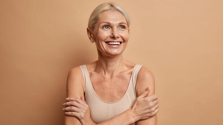Smiling older woman embracing herself